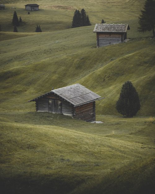 Free Charming wooden cabins scattered on lush green hills in Trentino-Alto Adige, Italy. Stock Photo