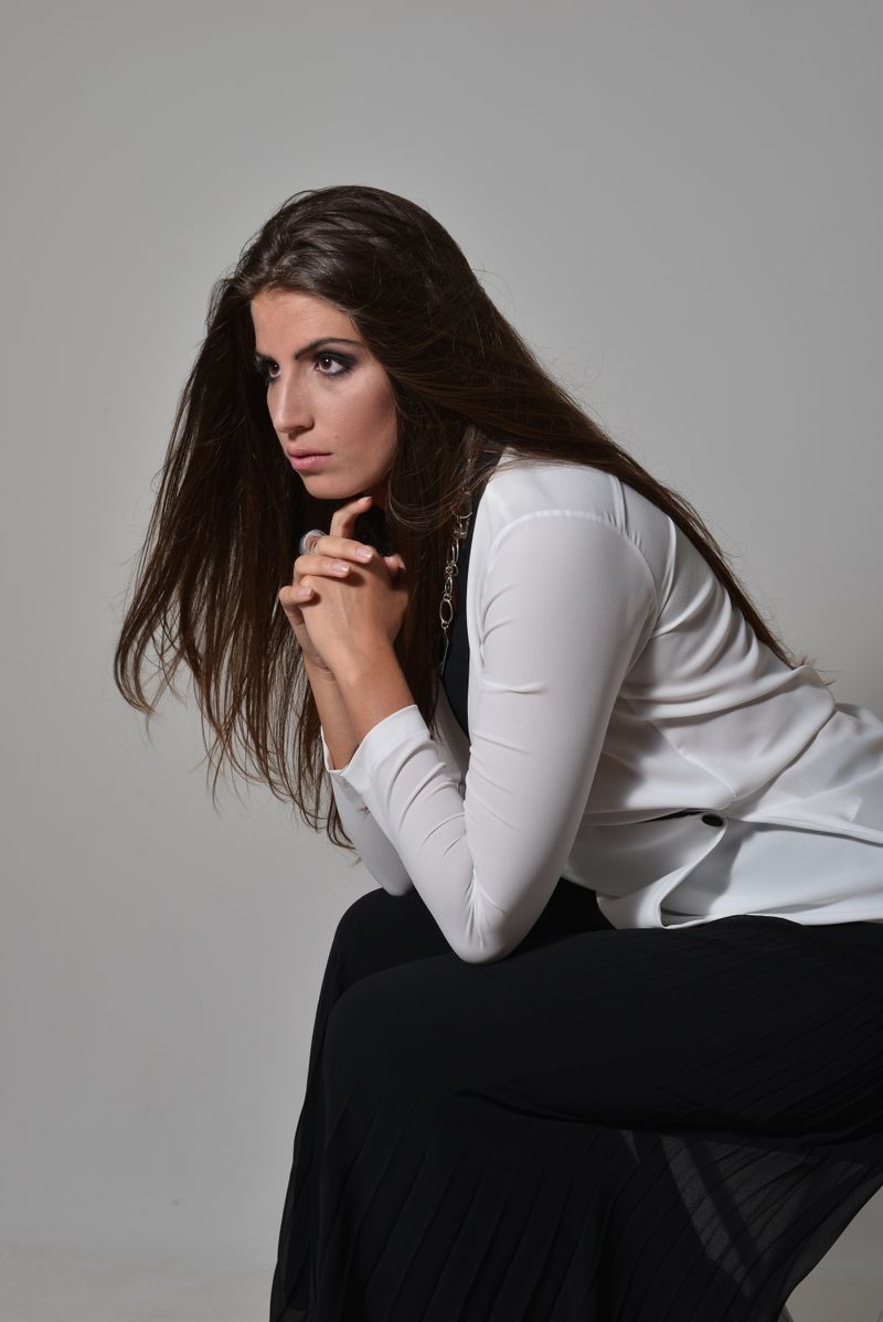 Pensive woman in a formal outfit sitting indoors
