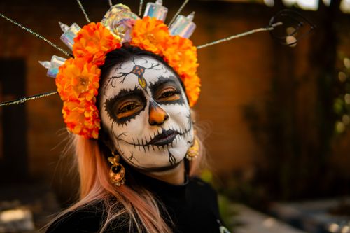 Free Woman with skeletal makeup and vibrant floral headdress, embodying Día de Muertos spirit. Stock Photo