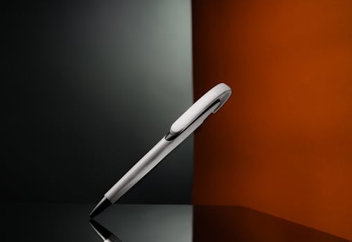 Elegant pen on reflective surface with artistic lighting, showcasing minimal design.