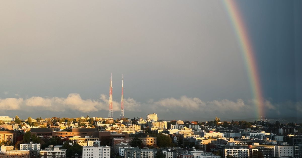 Beautiful rainbow over a cityscape with TV towers at dusk.