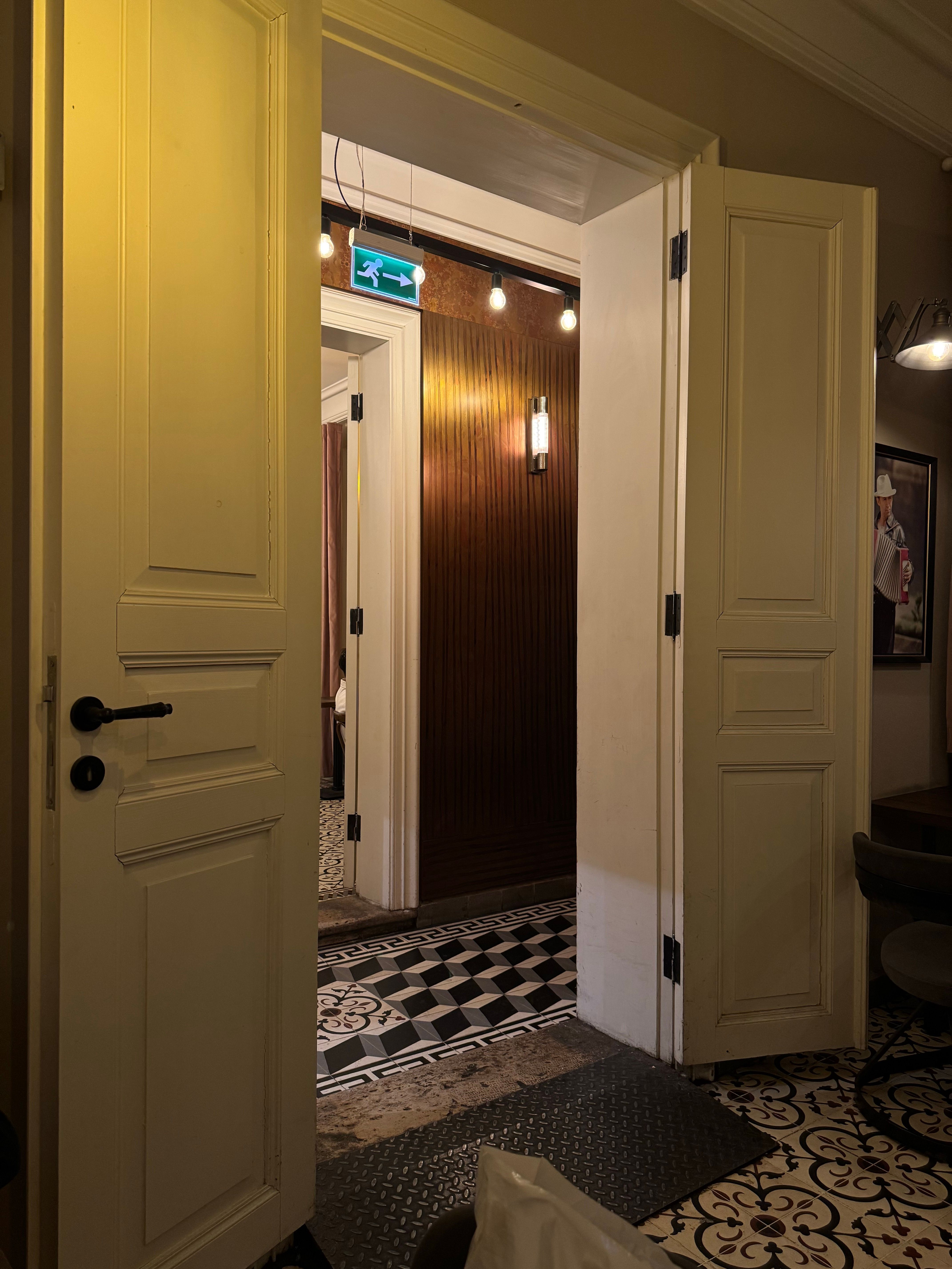 Free Elegant interior with open doors revealing a stylish hallway, showcasing intricate tile patterns and warm lighting. Stock Photo