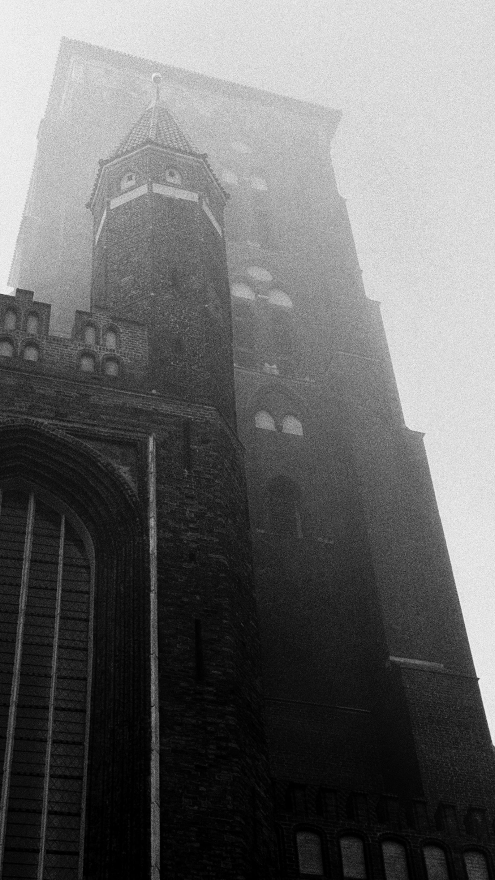 Tall Gothic tower disappearing into dense fog