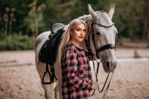 Free A woman in a plaid shirt standing beside a white horse outdoors. Stock Photo