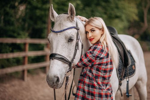 Free A woman with blonde hair lovingly embraces her white horse in a serene outdoor setting. Stock Photo