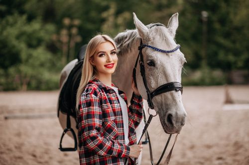 Free Young woman in plaid shirt smiling beside white horse outdoors. Stock Photo