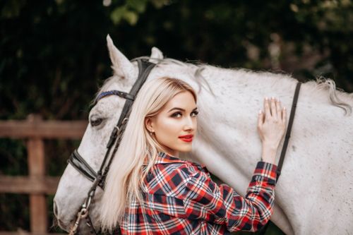 Free A woman in plaid shirt bonding with a white horse in an outdoor setting. Stock Photo