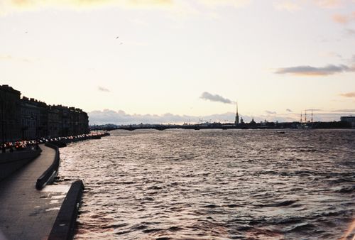 Free Serene riverside scene in St. Petersburg with distant city skyline and golden dusk sky. Stock Photo