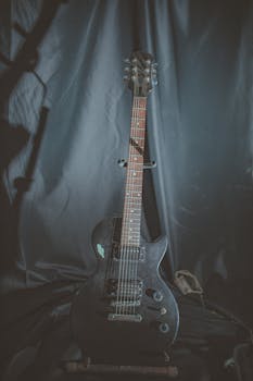 A stylish black electric guitar captured in a dimly lit indoor studio setting.