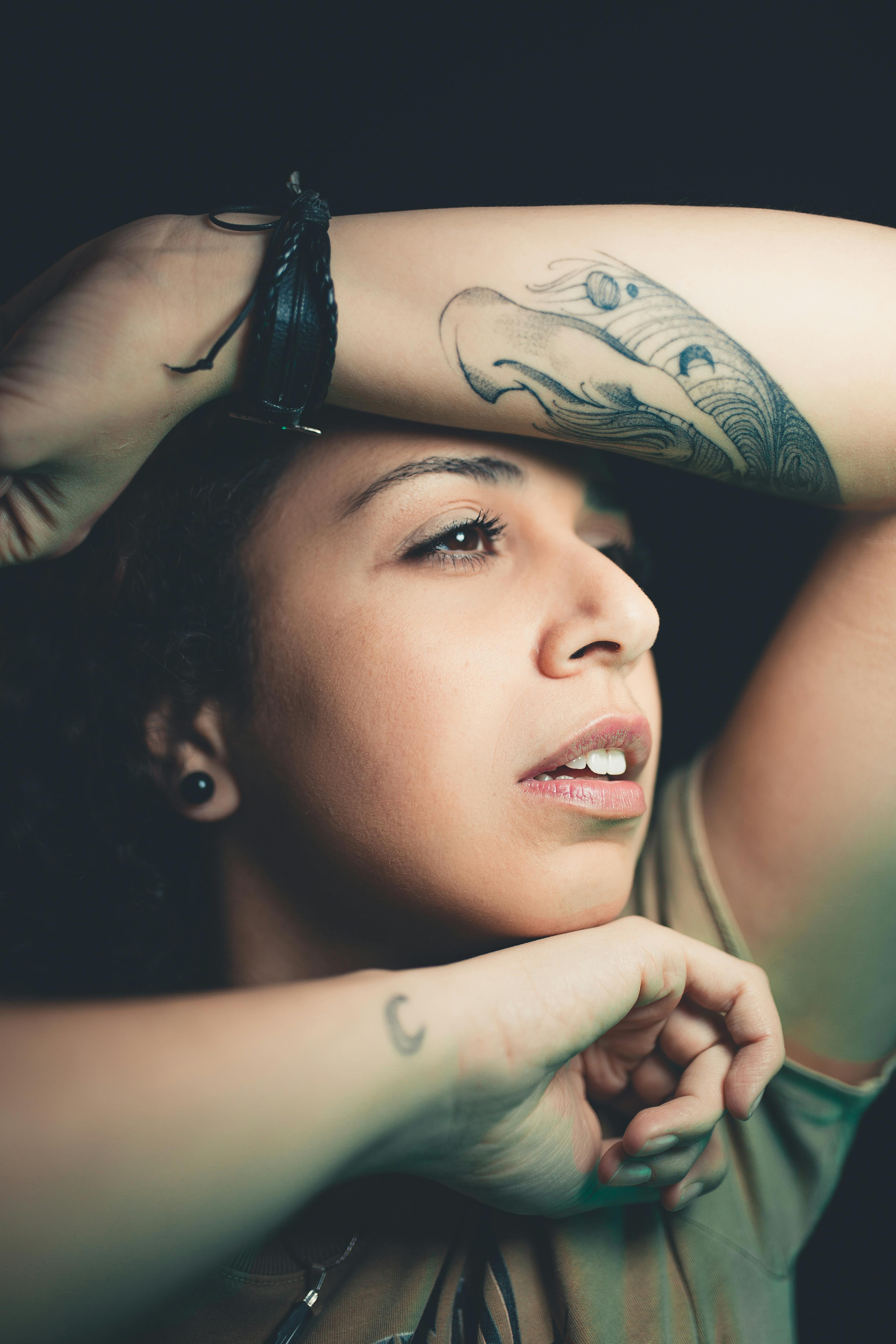 Close-up portrait of a woman with tattoos in a stylish pose, capturing modern beauty and fashion.