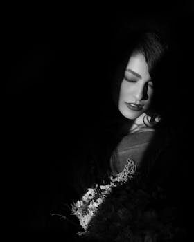 一幅忧郁的黑白肖像中，灯光照亮了女人的一部分