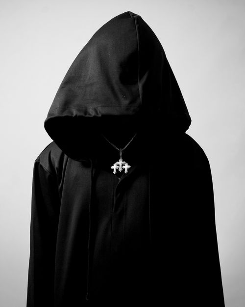 Free A hooded figure in a black cloak with a mysterious vibe, wearing a pendant. Stock Photo