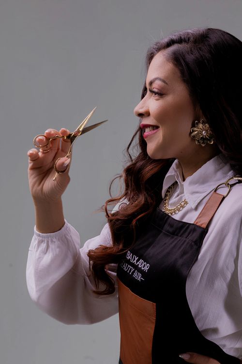 Free Confident female hairdresser holding scissors, ready for a haircut. Stock Photo