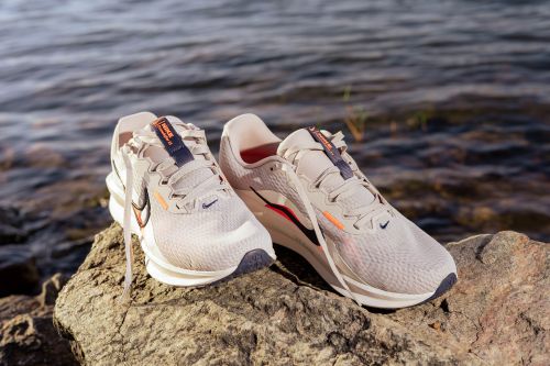 Free Pair of modern running shoes placed on a rock by the water, highlighting style and functionality. Stock Photo