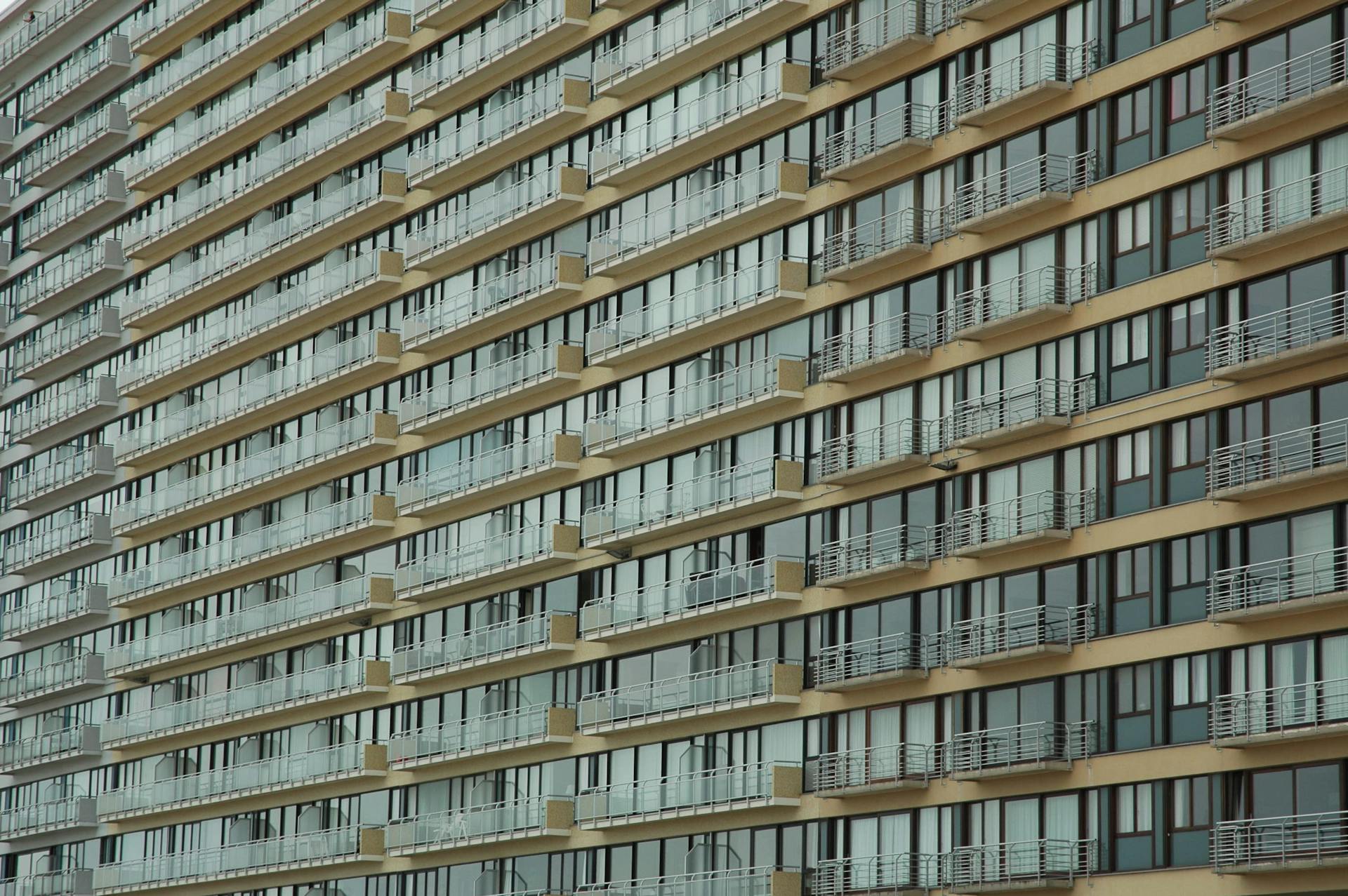 A detailed view of a modern apartment building facade with repeating balconies and glass windows.