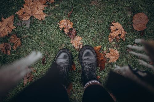 Free Top view of black boots on grass covered with autumn leaves, showcasing fall vibes. Stock Photo