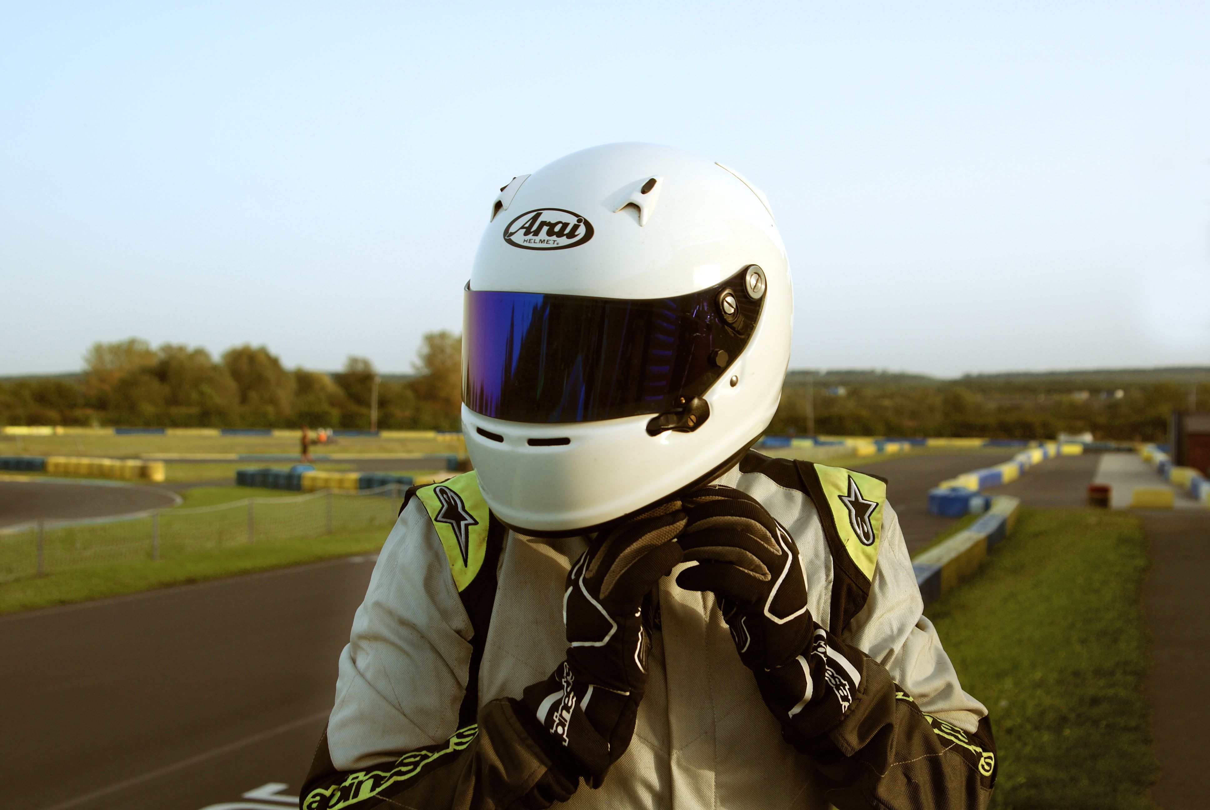 A karting racer adjusts their helmet on a race track in Normandie, France.
