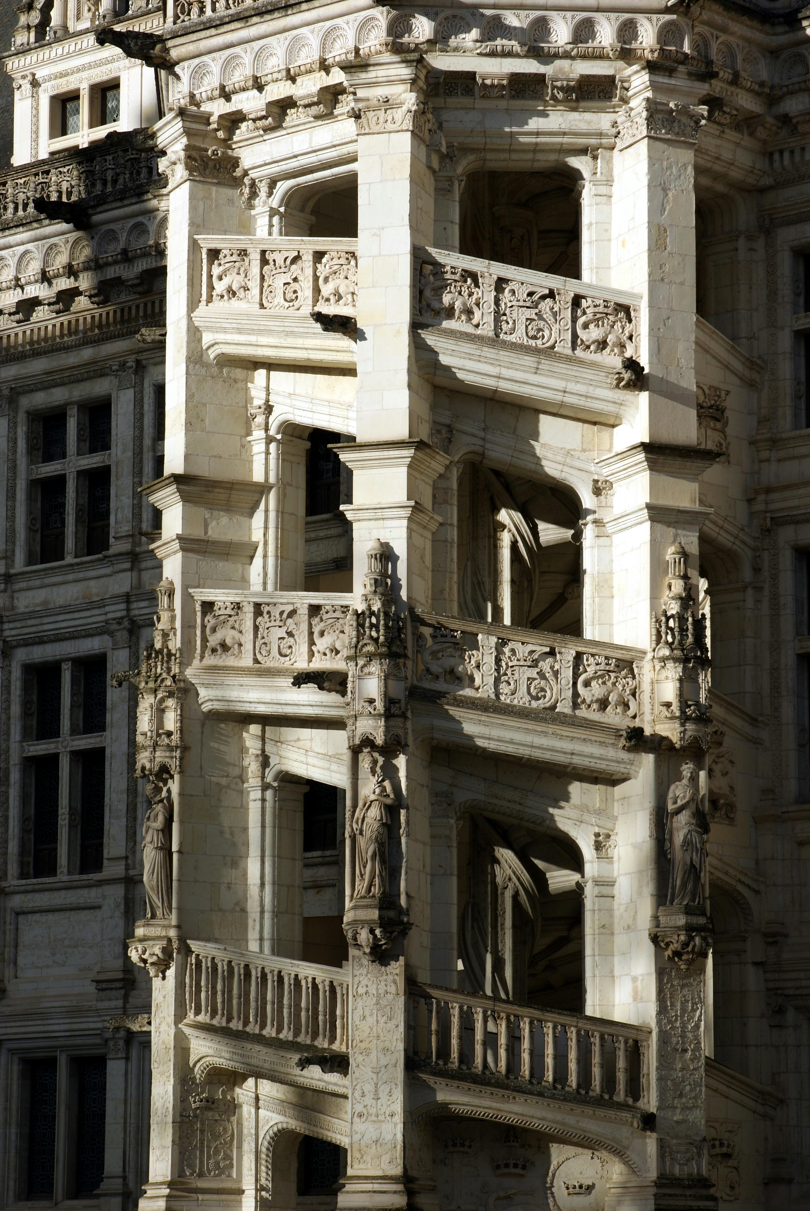 Detailed view of a spiral staircase on an ornate castle facade with marble architecture.