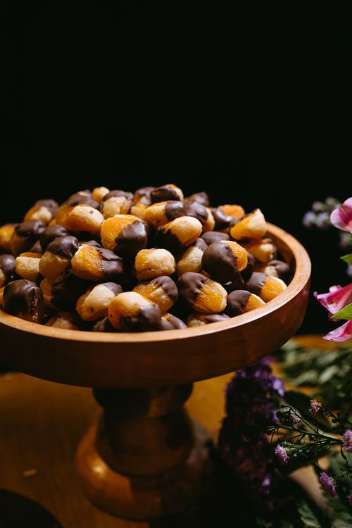 Free Assorted pastries dipped in chocolate on a wooden stand with floral decor. Stock Photo