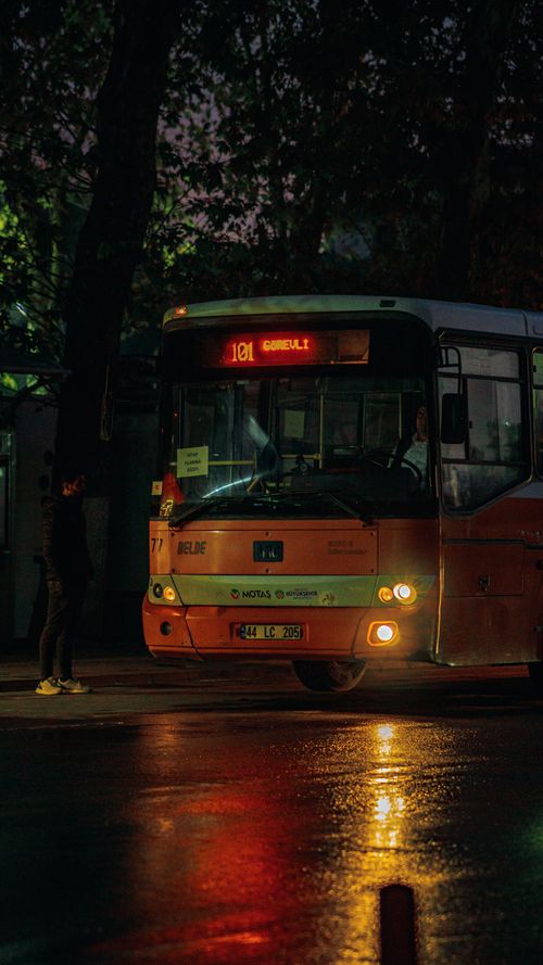 Free City bus at night reflecting street lights, capturing urban nightlife ambiance. Stock Photo