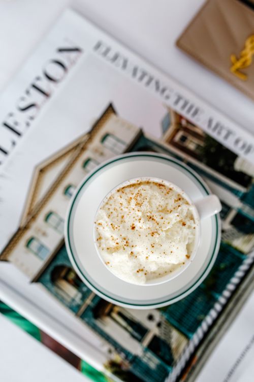 Free Overhead view of a coffee cup with whipped cream resting on stylish magazines. Stock Photo