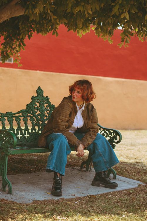 Free A young woman in casual wear enjoying a peaceful moment seated on a park bench. Stock Photo
