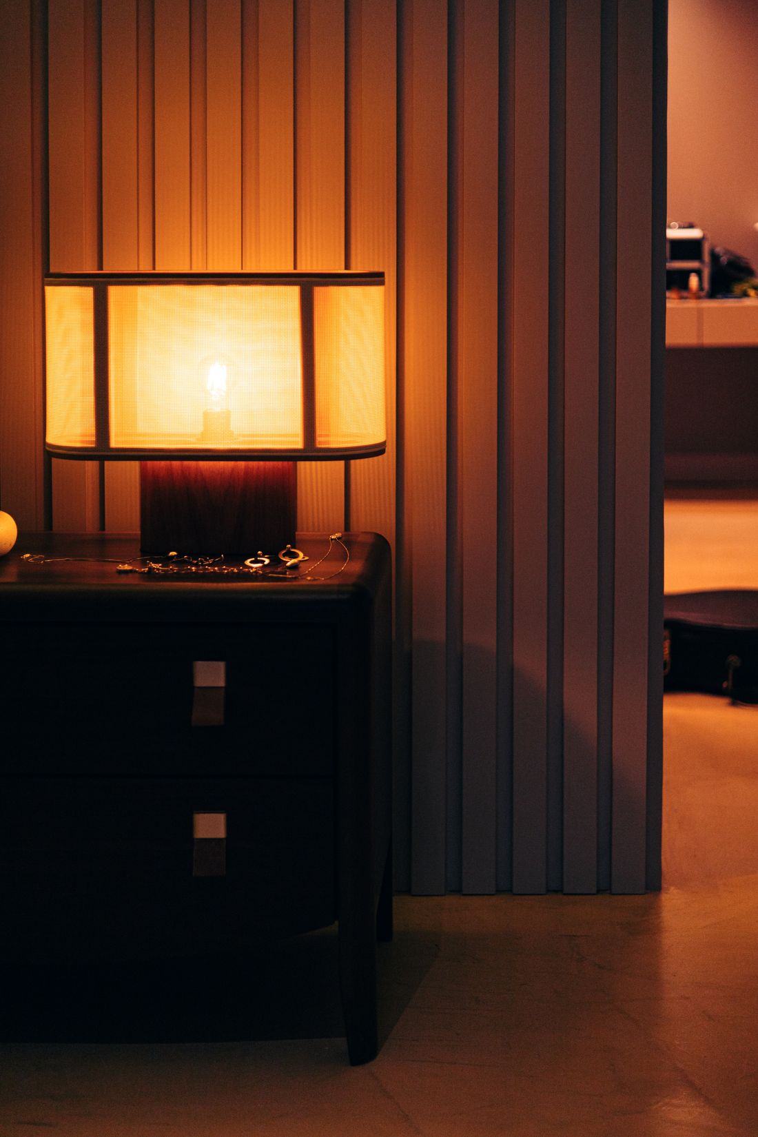 A shaded lamp glowing over a nightstand in a panelled room, photo by Bruna Correa on Pexels
