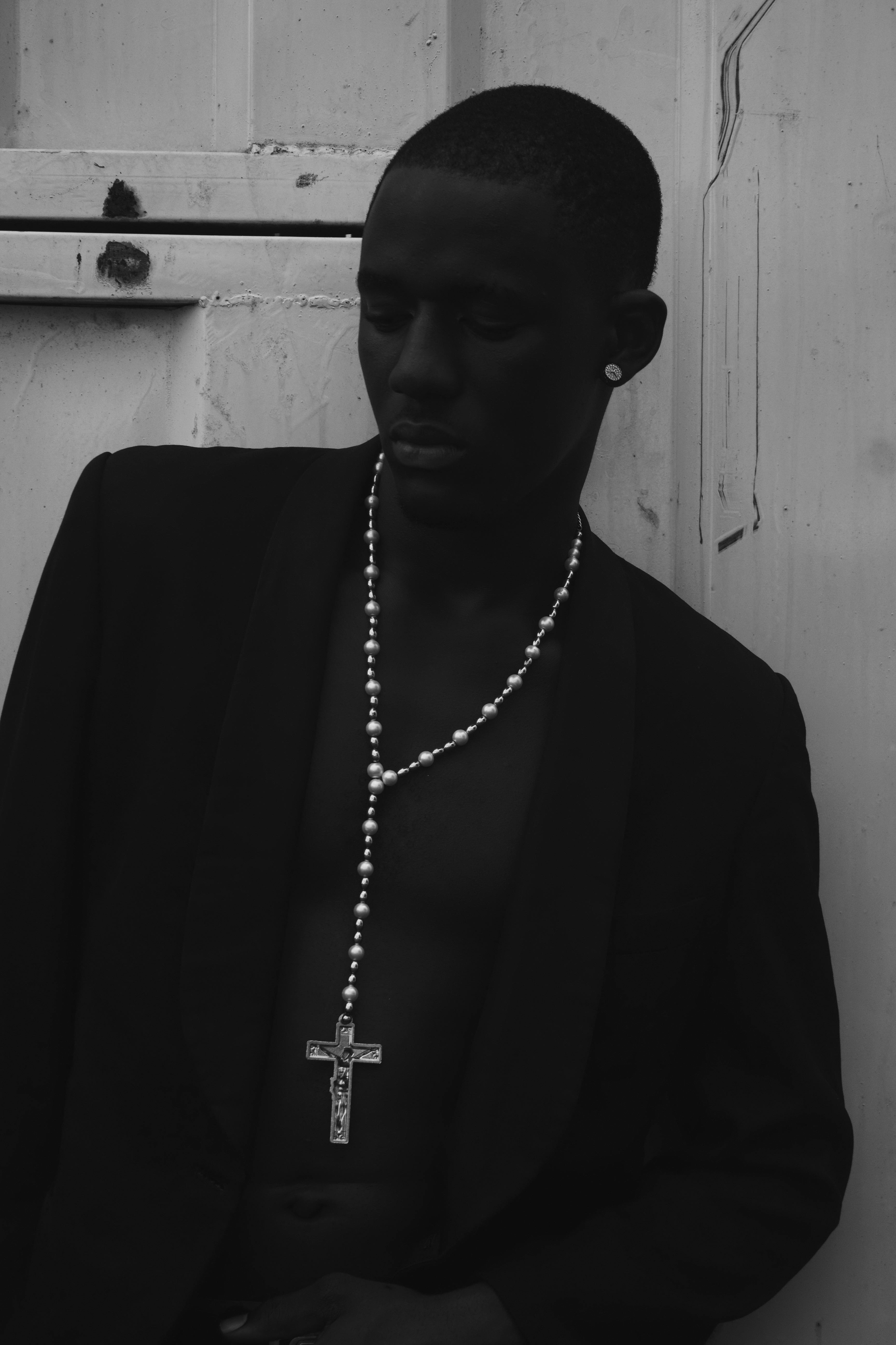 Black and white portrait of a contemplative man with a cross necklace in Nigeria.