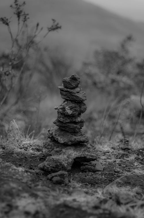 Free A black and white photo of a stacked rock cairn in a natural, misty setting. Stock Photo