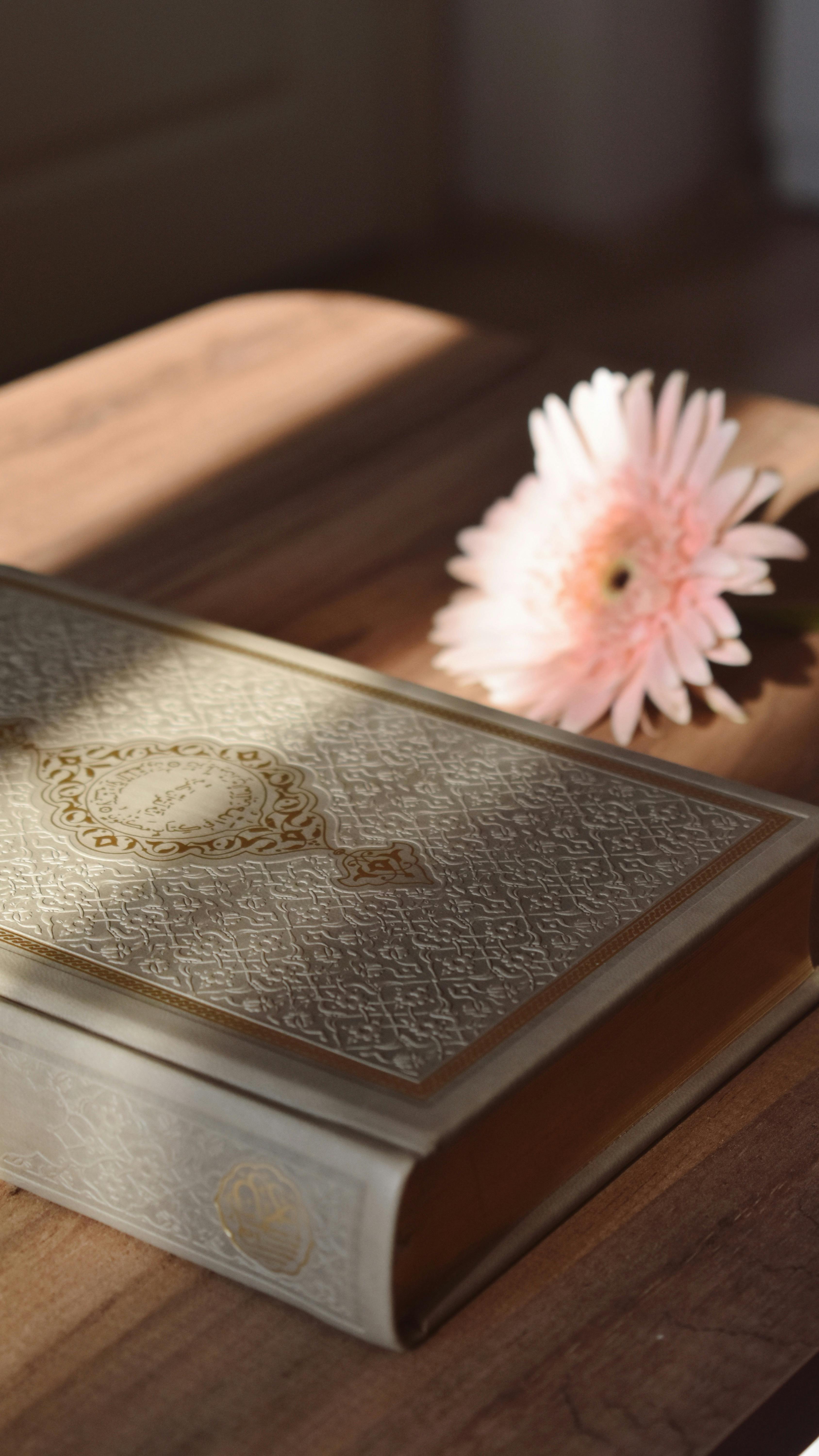 ornate book with pink flower on wooden table