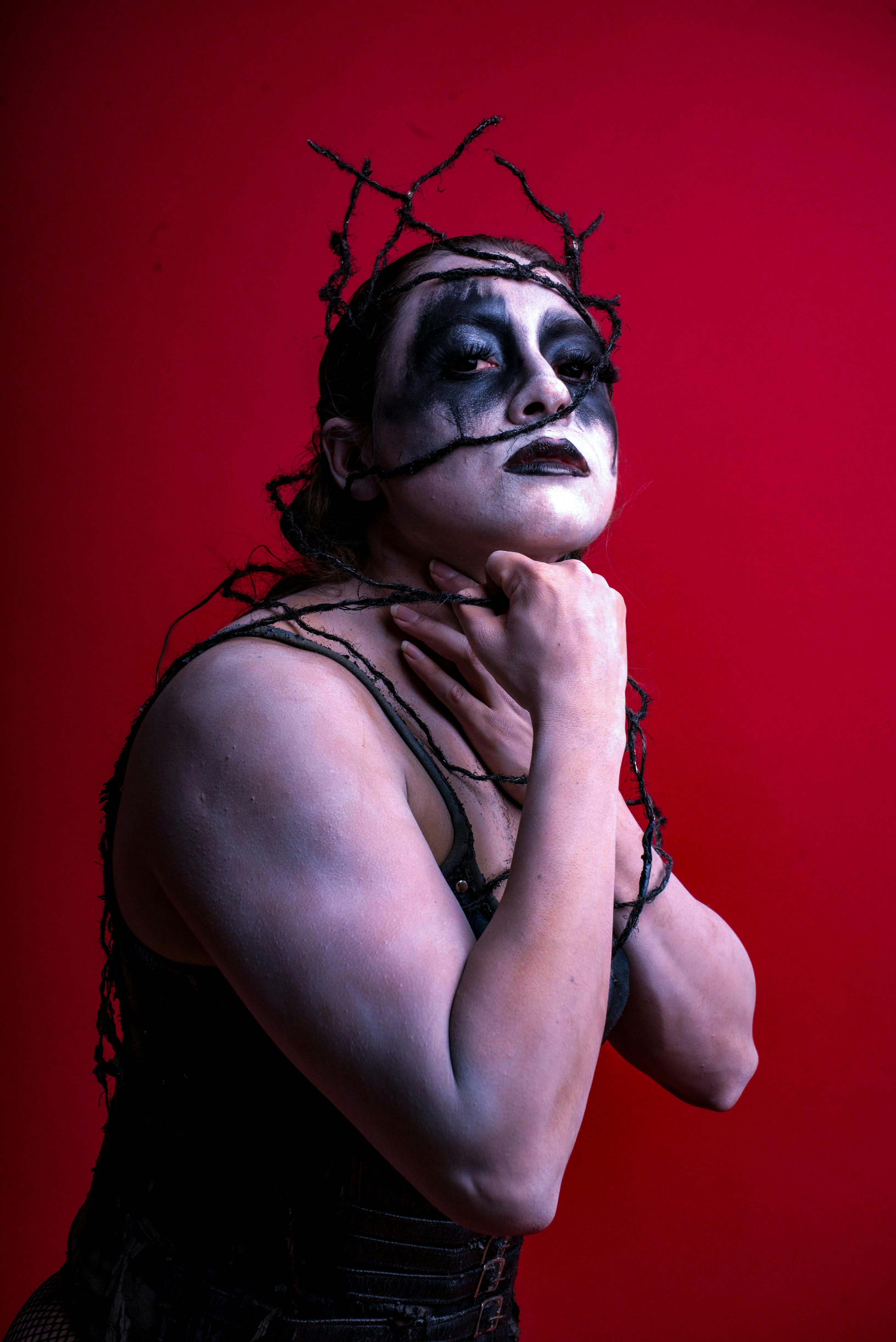 A powerful and expressive portrait showcasing gothic theme with bold makeup against a red background.
