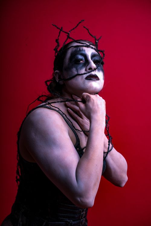 Free A powerful and expressive portrait showcasing gothic theme with bold makeup against a red background. Stock Photo