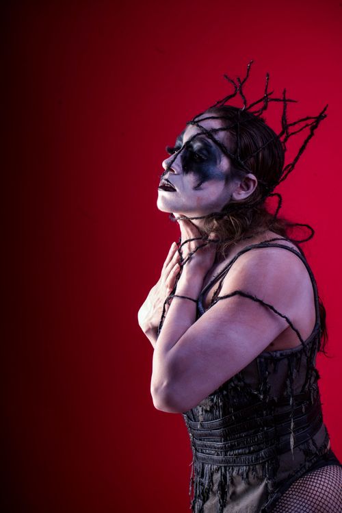 Free A striking portrait of a person in dramatic costume and face paint against a red background, highlighting theatrical art. Stock Photo