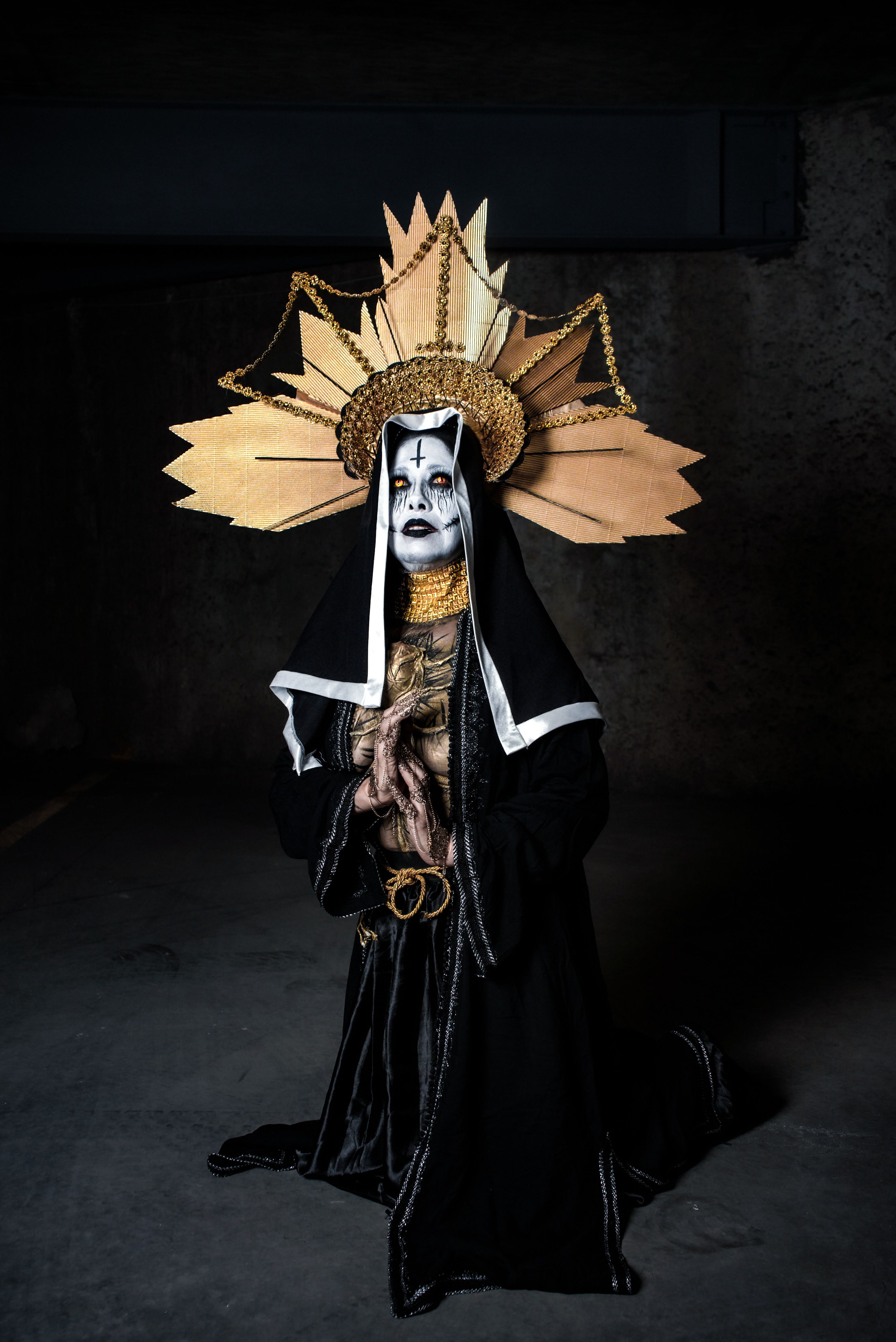 Person in intricate gothic costume and headpiece poses in dramatic lighting for unique artistic portrait.