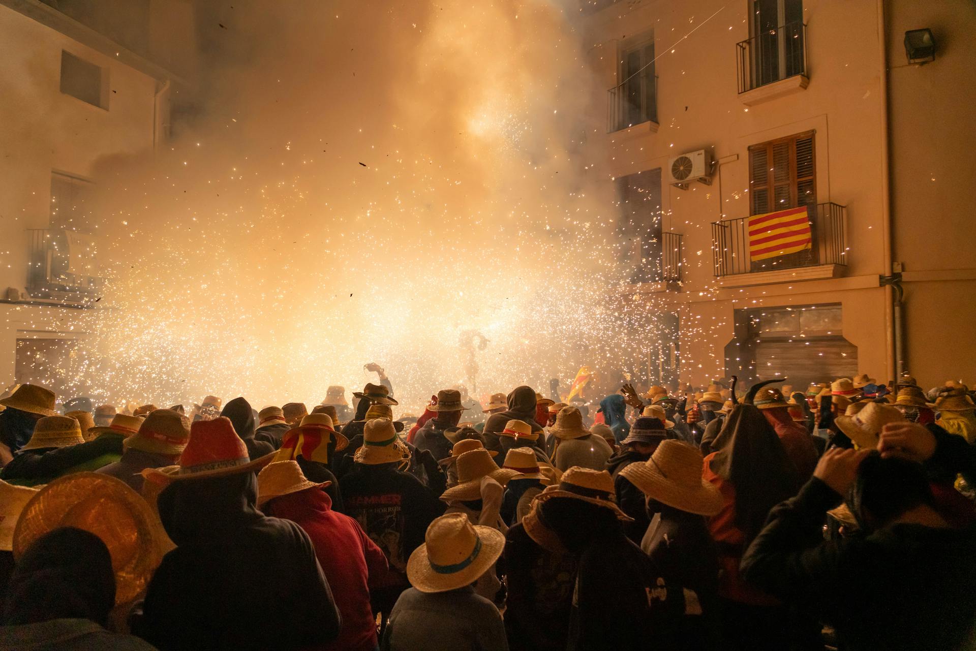 Crowd enjoying fireworks display in Les Borges Blanques, with traditional hats and Catalan flag visible.