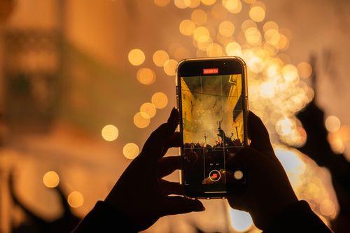 Free A person records a vibrant fireworks display using a smartphone at night. Stock Photo