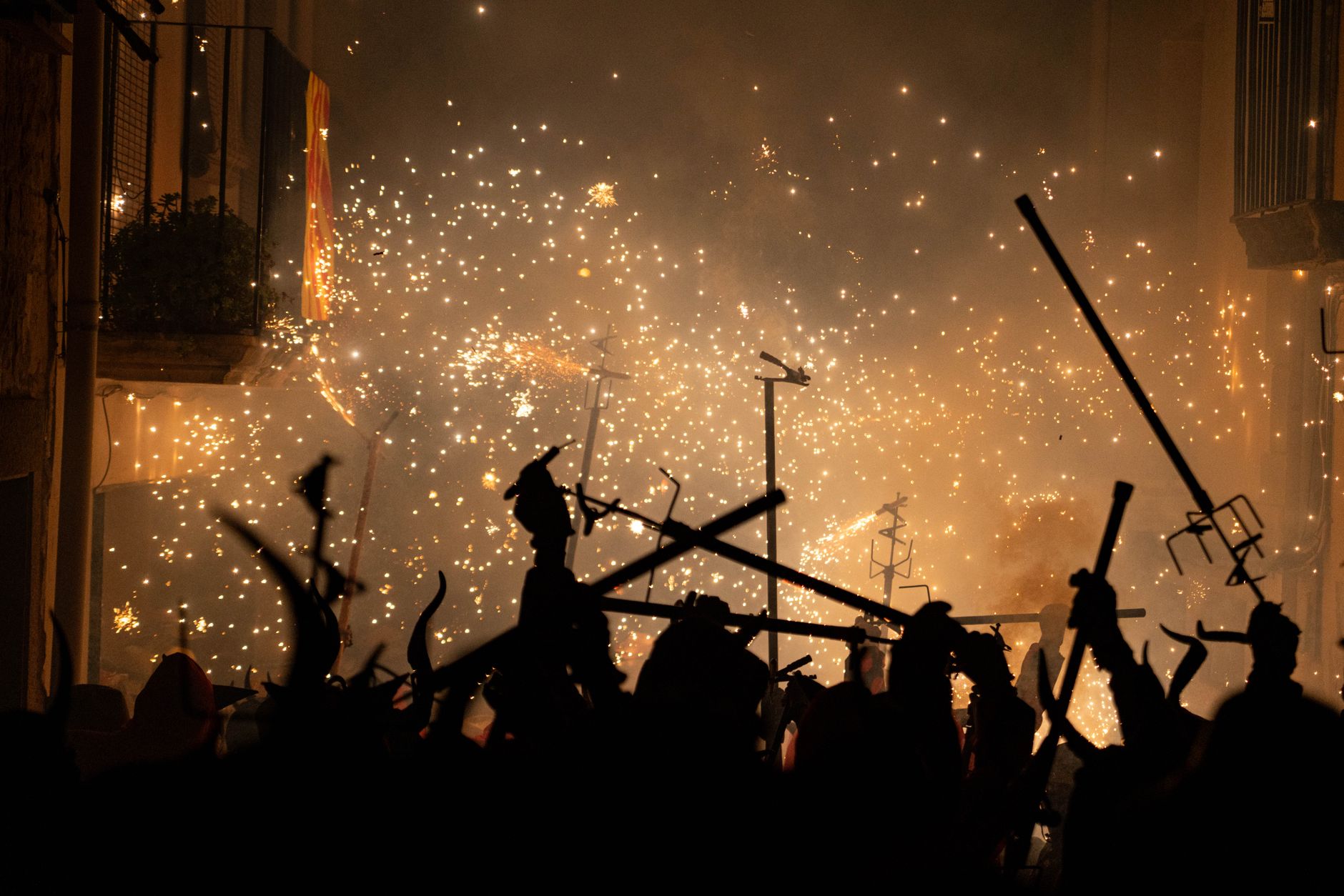 Silhouetted revelers beneath fireworks during a night festival in Les Borges Blanques, Catalonia, Spain.