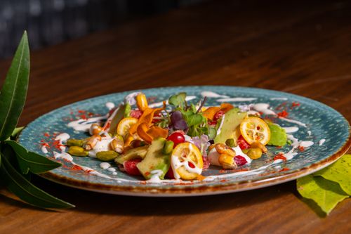 Free Vibrant gourmet salad featuring kumquats, microgreens, and avocado on ceramic plate. Stock Photo