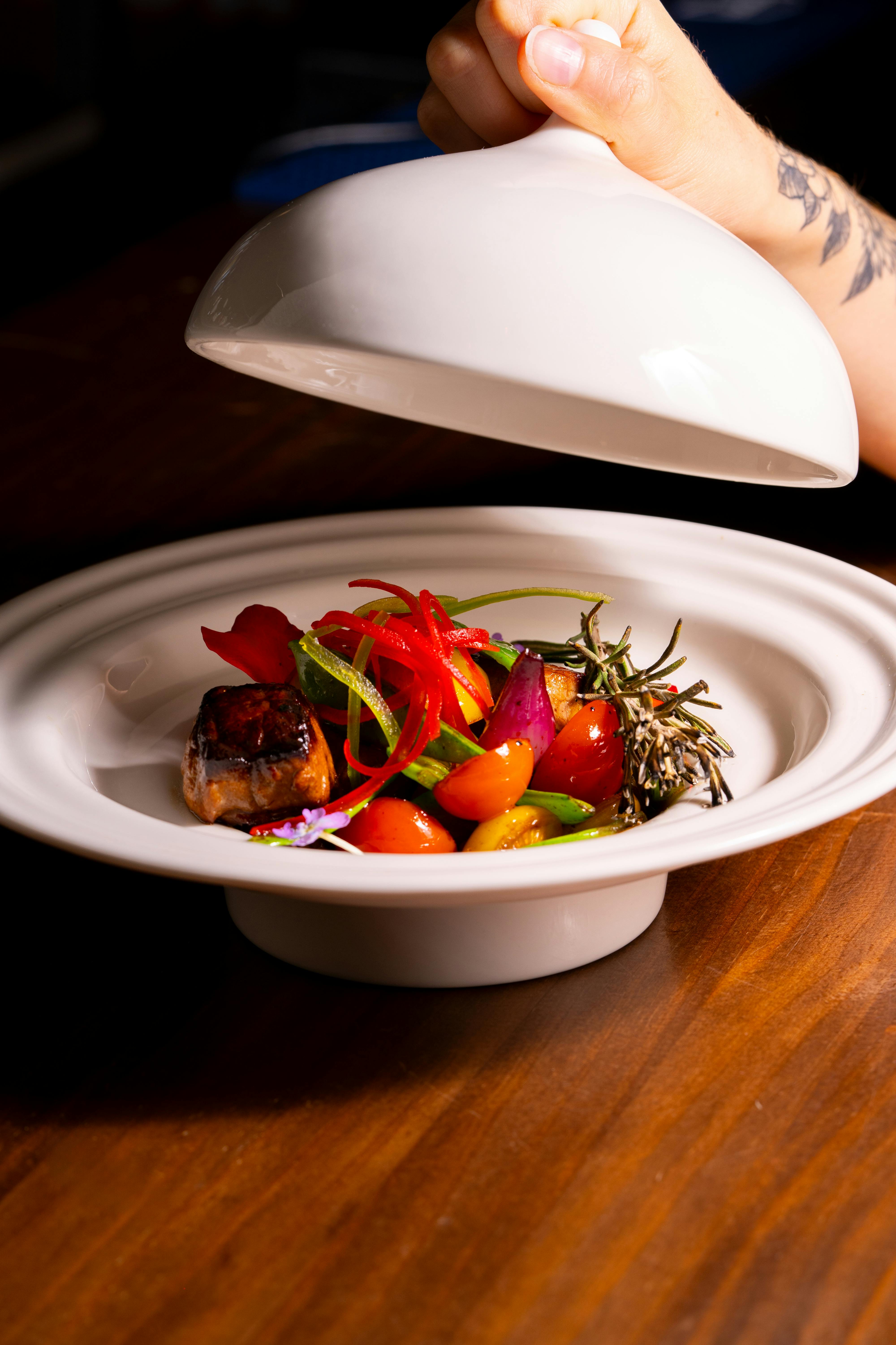 A chef unveiling a dish with a flourish, surrounded by judges and spectators