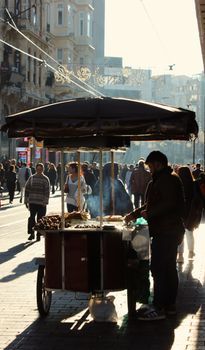 A busy street vendor selling food amidst a crowded urban scene in daylight.