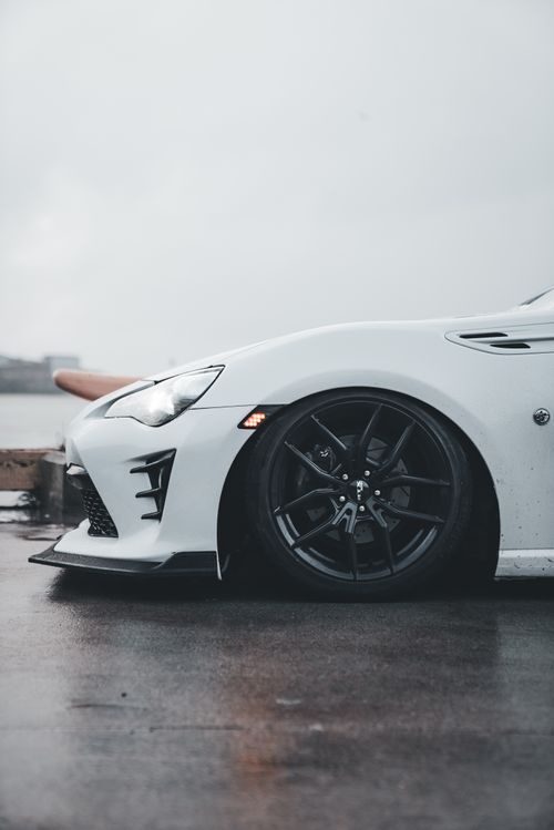 Free Artistic shot of a white sports car on a rainy day, highlighting sleek design and urban style. Stock Photo