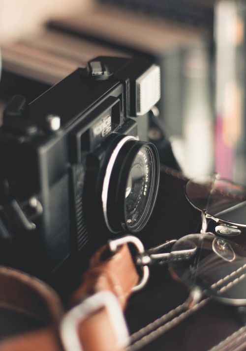 Free Close-up of a vintage camera with eyeglasses on a leather bag, evoking nostalgia. Stock Photo