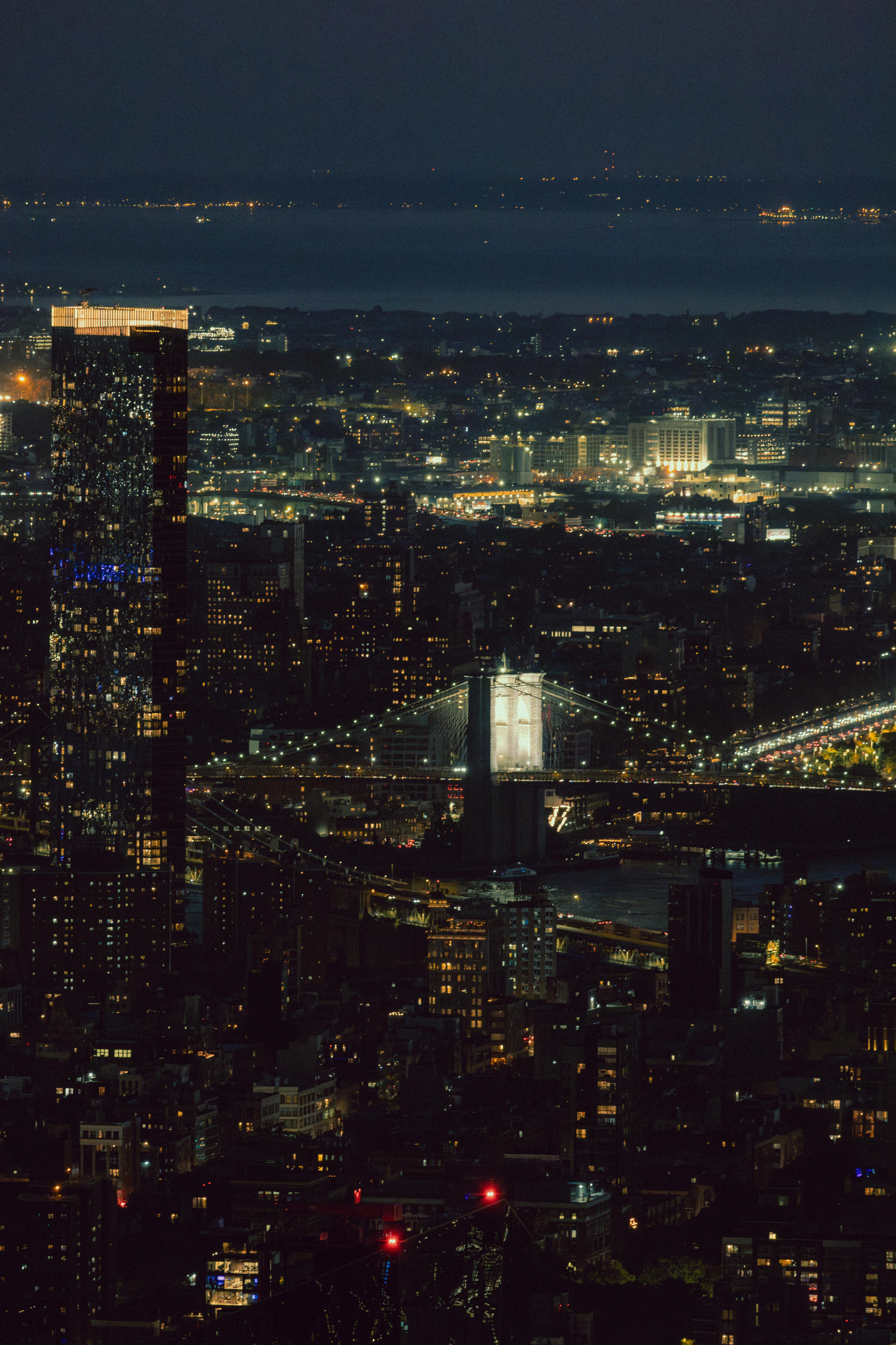 Stunning aerial view of Brooklyn Bridge at night, capturing city lights and skyline.