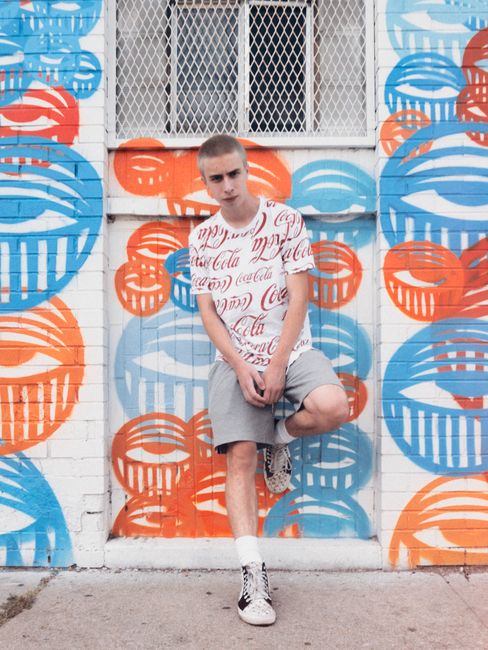 Stylish street portrait of a young man in Denver with colorful graffiti background.