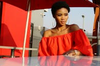 白天，一位身着红色连衣裙的优雅女子在城市中撑着伞，若有所思地摆着姿势