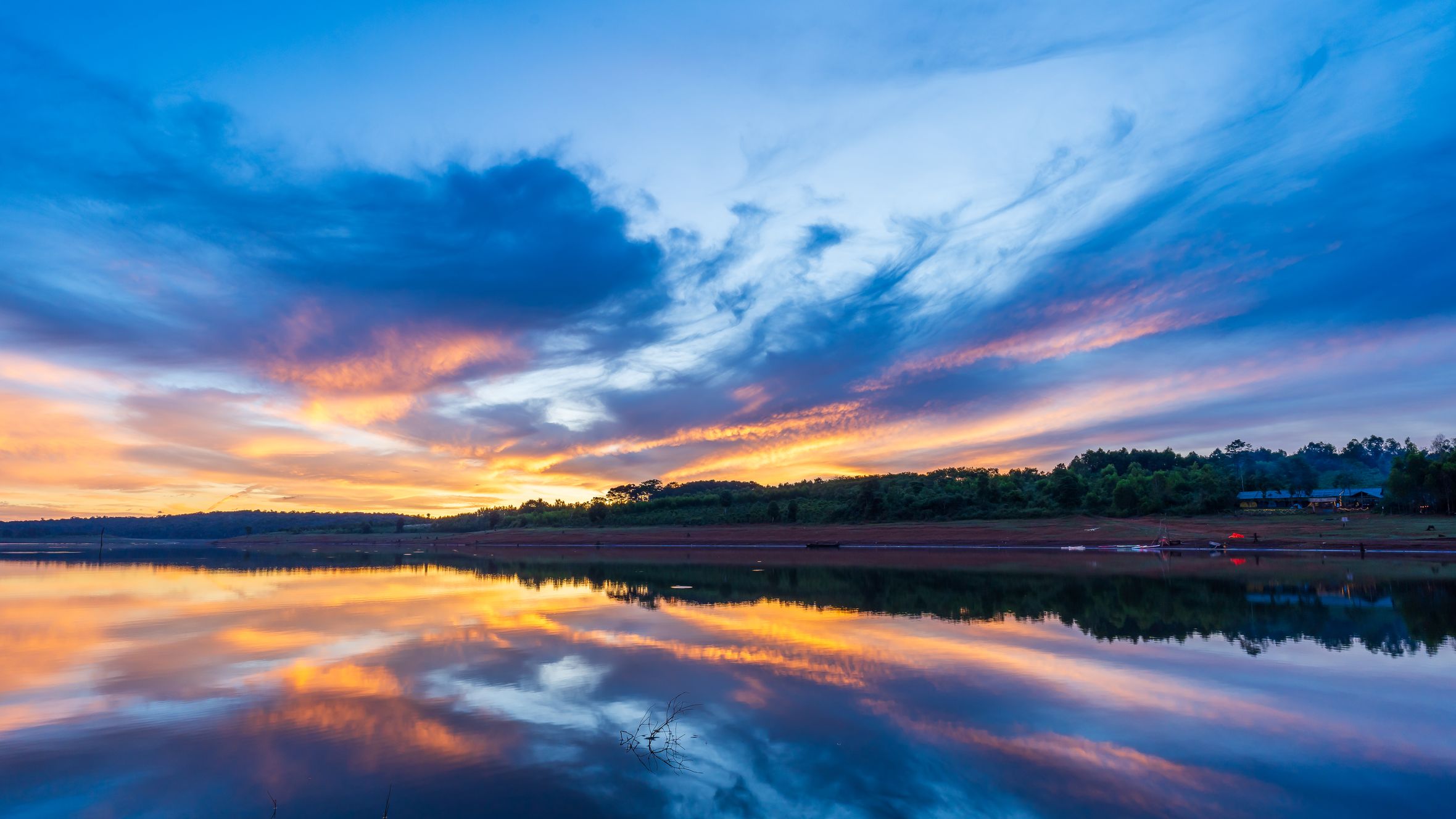 Captivating sunrise reflection on Gia Lai lake with vibrant clouds in Vietnam.