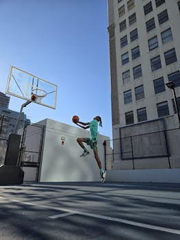 Dynamic shot of a young player performing a slam dunk on an urban outdoor basketball court.