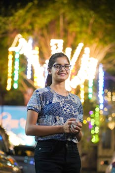 A stylish young woman poses outdoors in a vibrant, neon-lit urban setting, embodying trendy nightlife vibes.