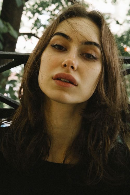 Free A close-up portrait capturing the thoughtful expression of a young woman outdoors. Stock Photo