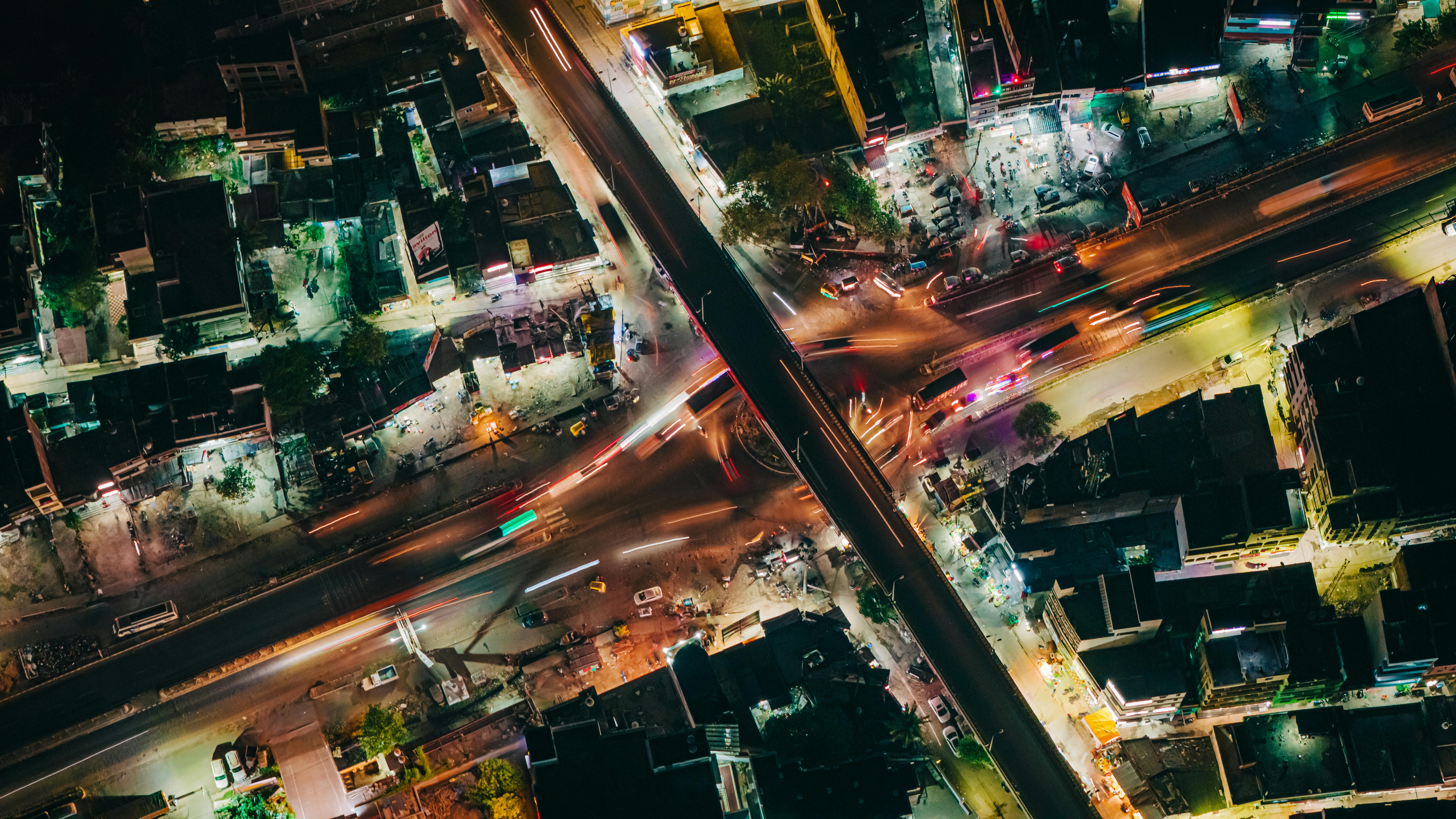 Dynamic aerial cityscape of a bustling night intersection in Muzaffarpur, showcasing vibrant light trails and urban infrastructure.